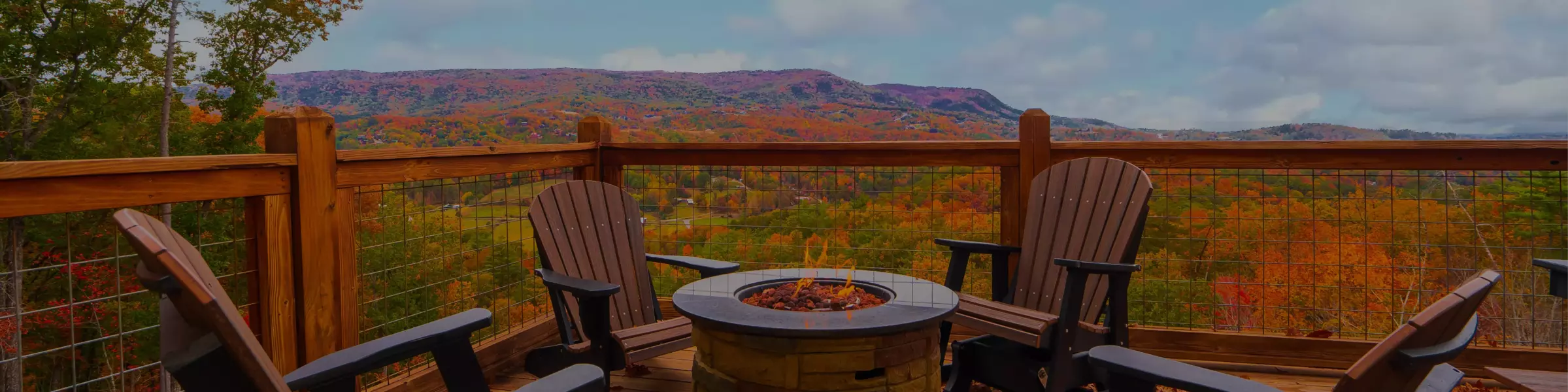 fire pit on deck of Smoky Mountain cabin with mountains covered in fall foliage in background