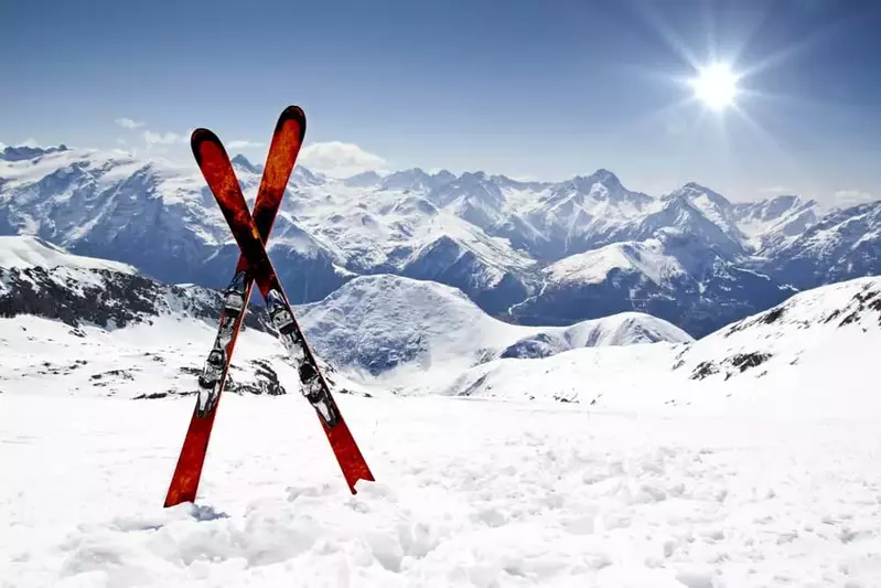 snow skis in the snow with mountains in the background