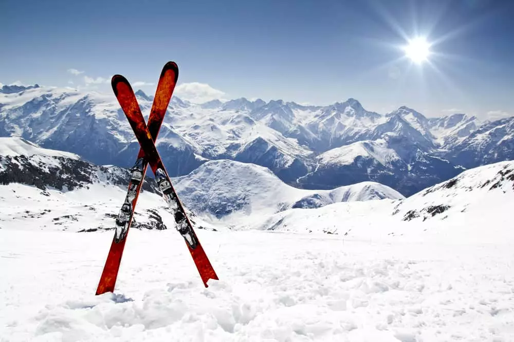 snow skis in the snow with mountains in the background