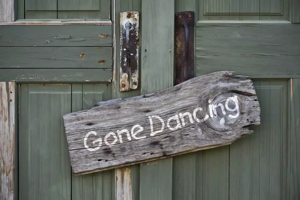 Sign hanging on green door says Gone Dancing