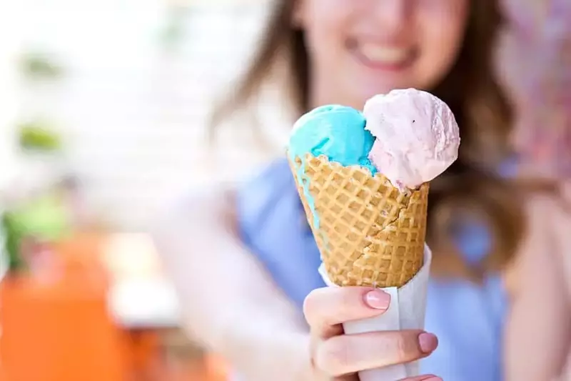 A woman with two scoops of ice cream in a cone.