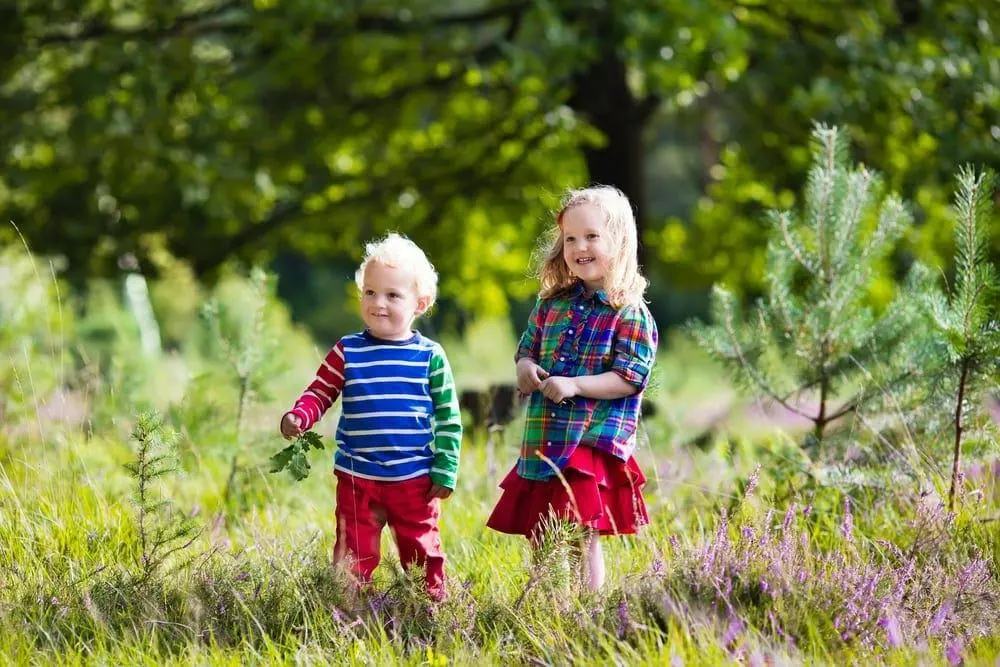 A toddler and his older sister in nature.