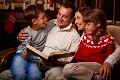 A family reading a Christmas story together on a couch.