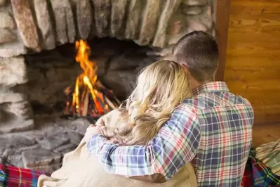 A couple relaxing in front of a stone fireplace.