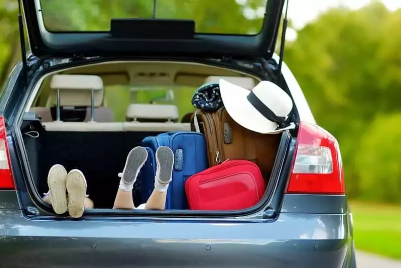 Two young sisters with thier feet up in the back of a car with suitcases.