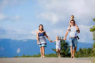 Family of four walking on a paved road in the mountains.