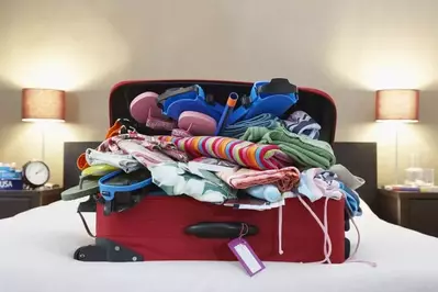 A very full suitcase on a bed.