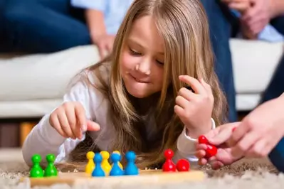 A little girl playing a board game with her family.