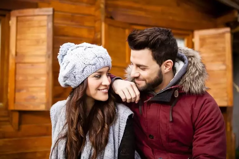 Happy couple in winter clothing outside one of our romantic cabins in Gatlinburg.