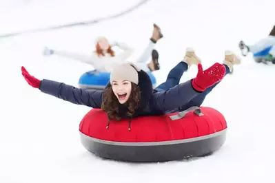 A group of young women snow tubing down a mountain.