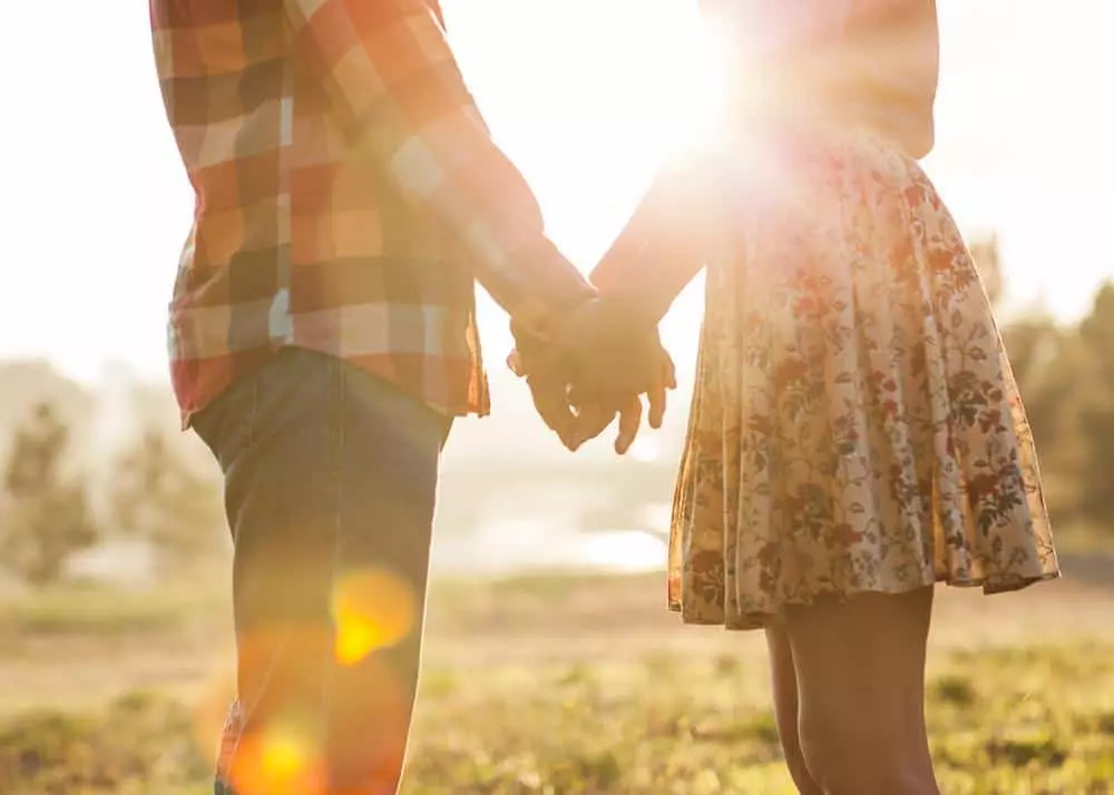 Romantic couple standing in the Smoky Mountains, holding hands as the sun sets