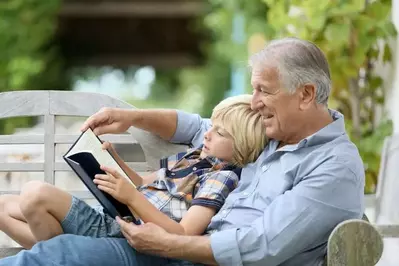 Grandfather smiling while reading a story to his grandson on the deck of an affordable Gatlinburg cabin rental