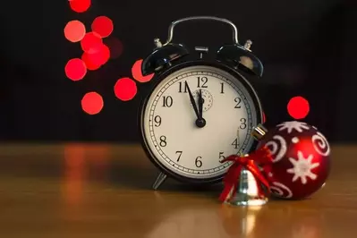 Clock sitting next to a Christmas ornament and bell