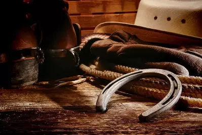 Western horse riding gear with cowboy hat, cowboy boots, horse shoe, and lasso