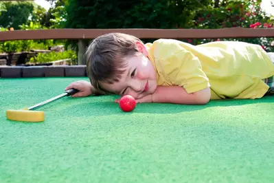 Kid laying on mini golf course